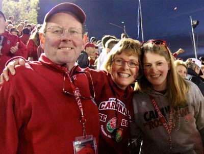 Three smiling family members in the stands at a game